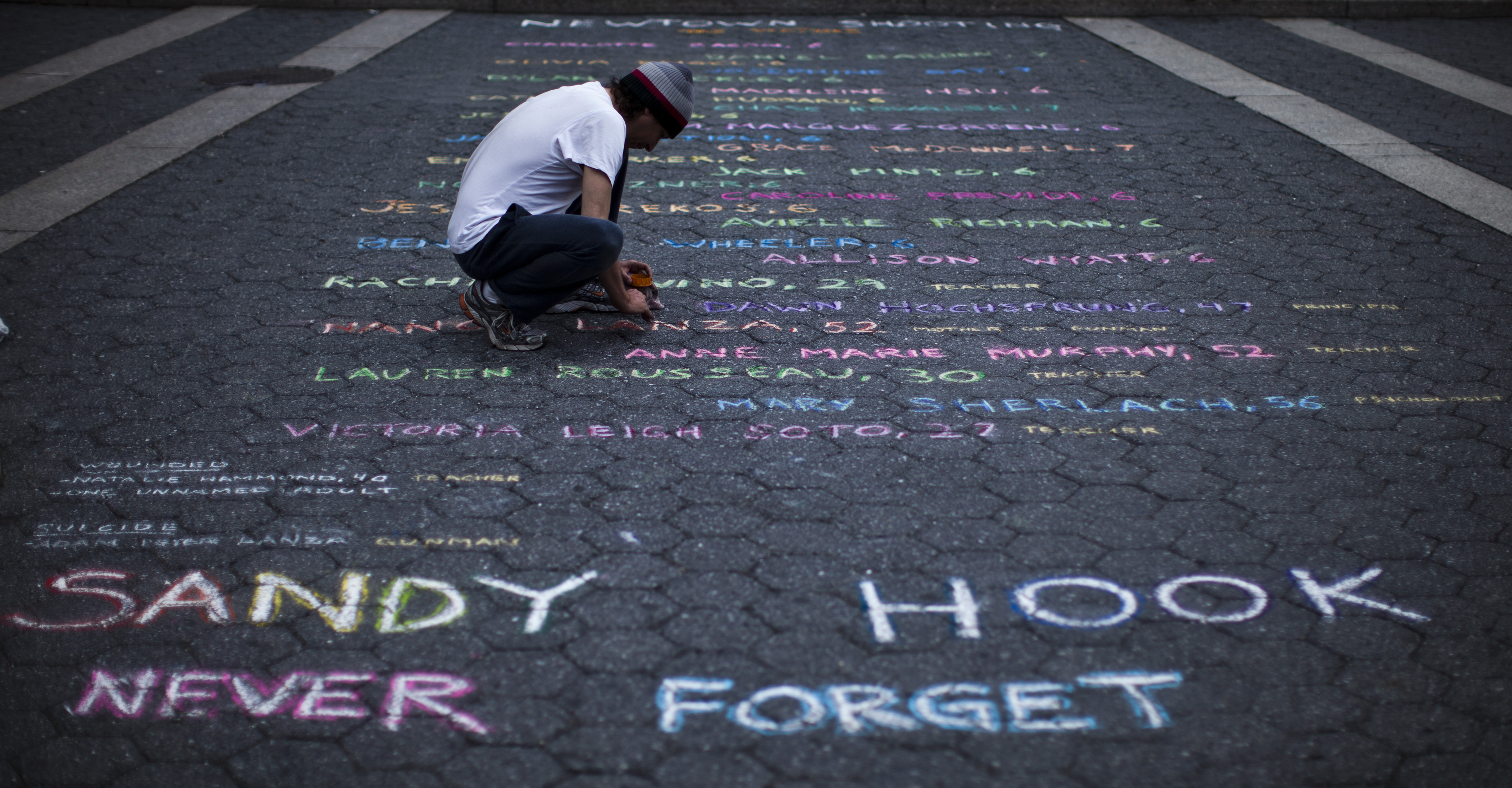 Street artist Mark Panzarino, 41, prepares a memorial as he writes the names of the Sandy Hook Elementary School victims during the six-month anniversary of the massacre, at Union Square in New York, June 14, 2013. Six months after a gunman killed 26 children and adults at the elementary school, families and local officials marked the day by honoring the victims and renewing the fight for stricter gun control. REUTERS/Eduardo Munoz (UNITED STATES - Tags: CIVIL UNREST EDUCATION CRIME LAW ANNIVERSARY TPX IMAGES OF THE DAY) - RTX10O9G